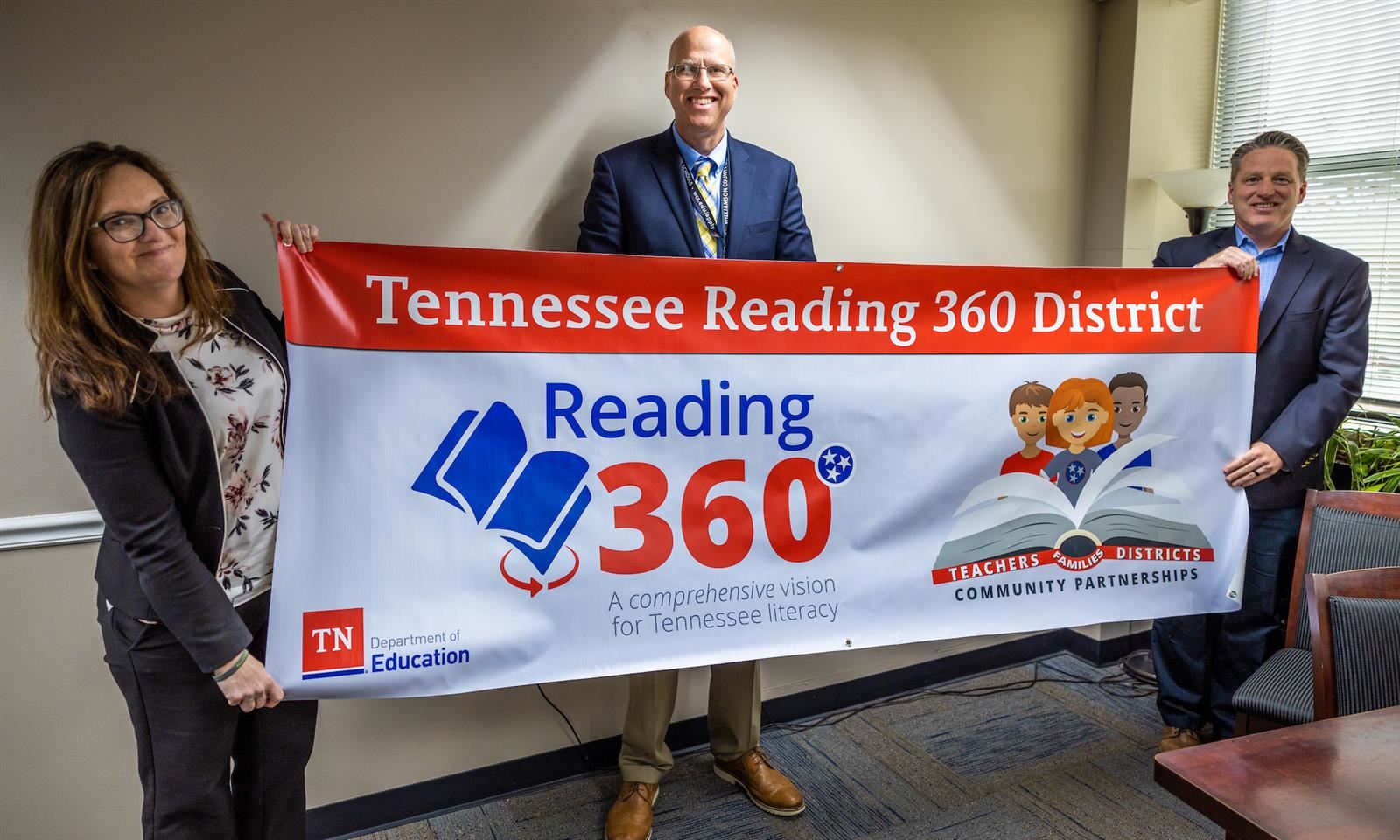 Three administrators hold a banner up